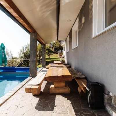 The covered terrace features a traditional wooden table with benches.